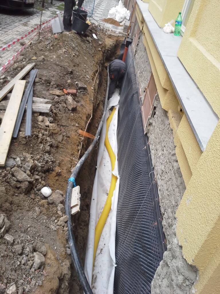 Výkop popri dome s nopovou fóliou a drenážnou rúrou pri izolácii základov
